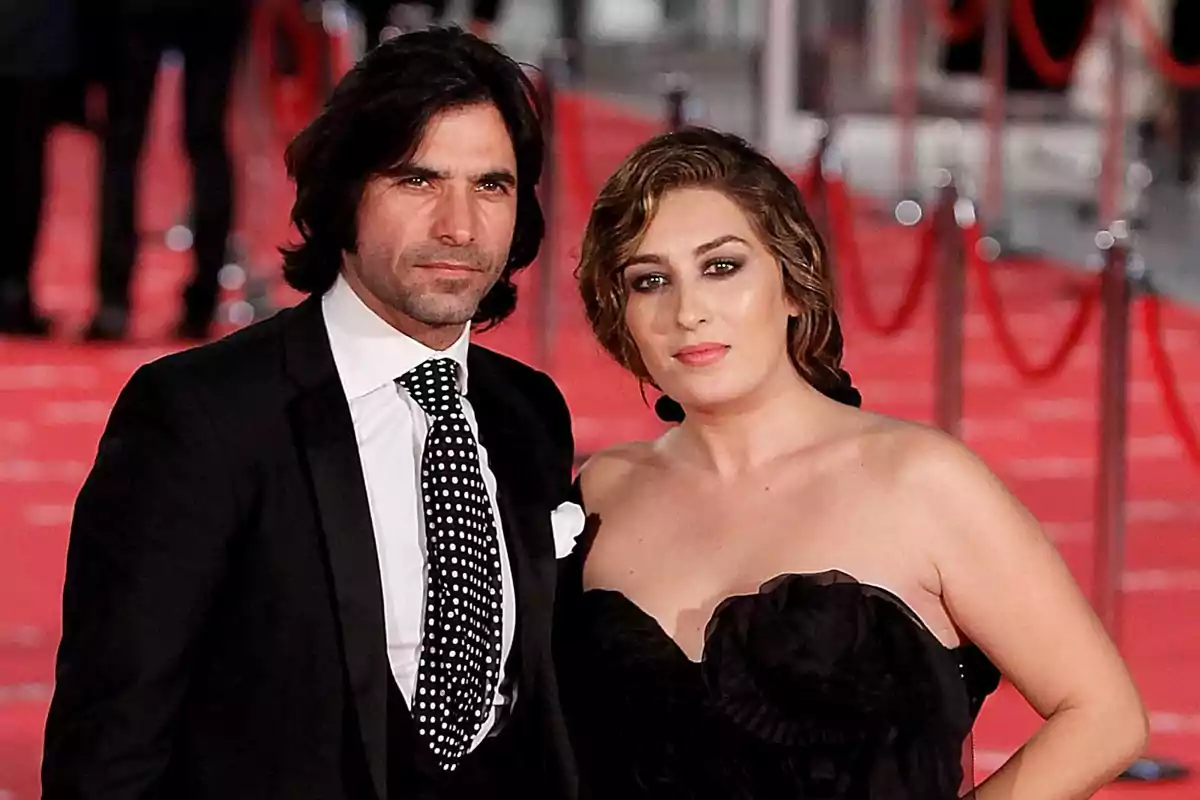 Pareja posando elegantemente en una alfombra roja con fondo desenfocado y cuerdas rojas