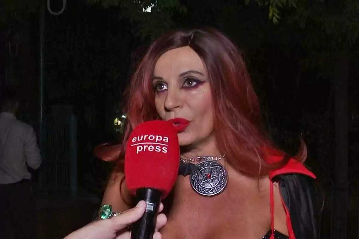 Mujer con peluca roja y maquillaje llamativo siendo entrevistada por un micrófono rojo de europa press durante la noche Mujer con peluca roja y maquillaje llamativo siendo entrevistada por un micrófono rojo de europa press durante la noche