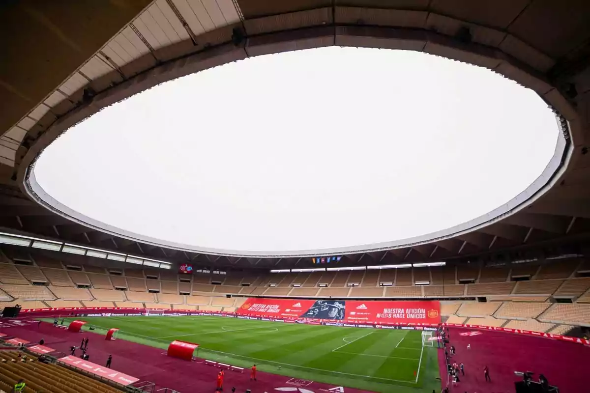 Estadio de fútbol vacío con gradas amarillas y carteles rojos alrededor del campo Estadio de fútbol vacío con gradas amarillas y carteles rojos alrededor del campo