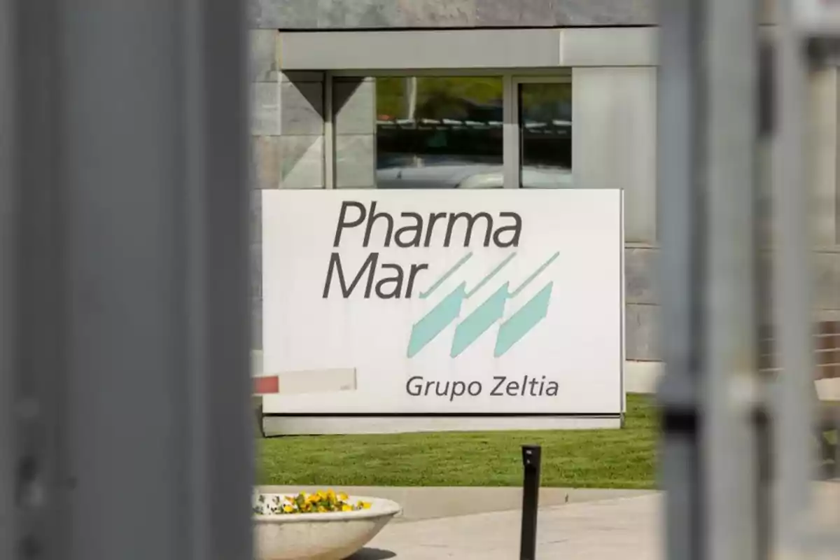 Cartel de la empresa PharmaMar Grupo Zeltia frente a un edificio con ventanas y césped Cartel de la empresa PharmaMar Grupo Zeltia frente a un edificio con ventanas y césped