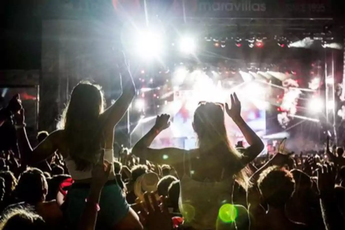 Personas disfrutando de un concierto al aire libre con luces brillantes y ambiente festivo Personas disfrutando de un concierto al aire libre con luces brillantes y ambiente festivo