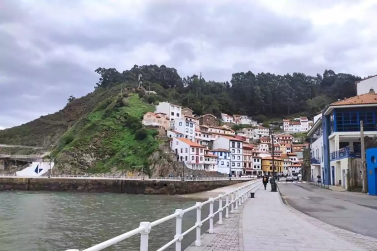 Pueblo costero con casas coloridas en la ladera de una colina junto al mar y un paseo peatonal en primer plano Pueblo costero con casas coloridas en la ladera de una colina junto al mar y un paseo peatonal en primer plano