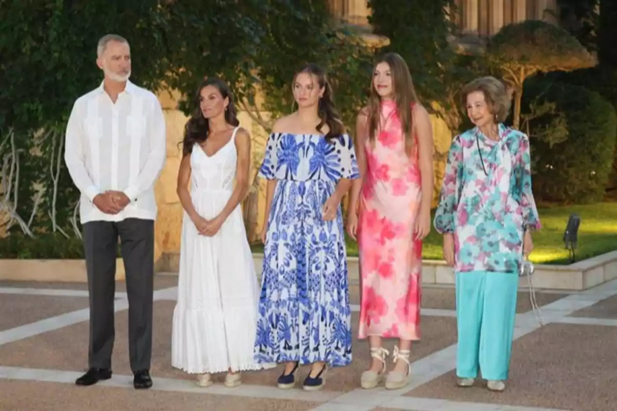 Five people pose outdoors dressed in stylish summer clothing in a landscaped setting. Five people pose outdoors dressed in stylish summer clothing in a landscaped setting.