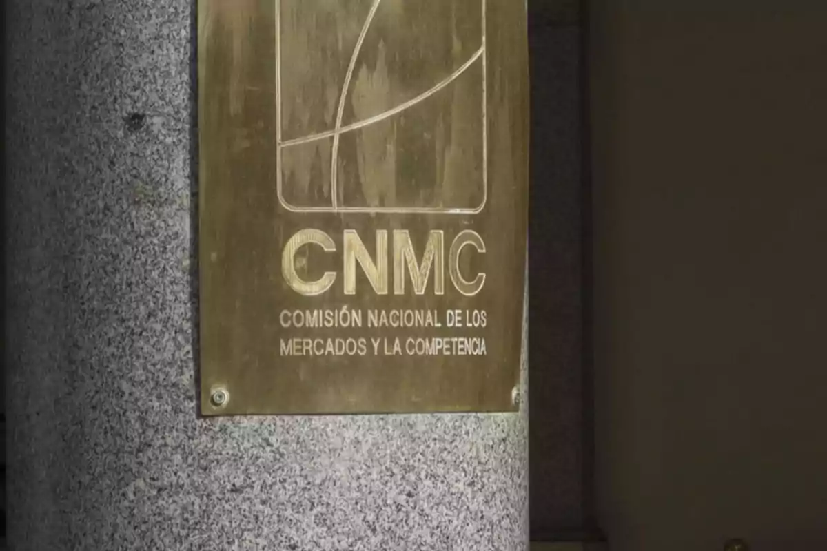 Placa dorada de la Comisión Nacional de los Mercados y la Competencia CNMC colocada sobre una columna de piedra Placa dorada de la Comisión Nacional de los Mercados y la Competencia CNMC colocada sobre una columna de piedra