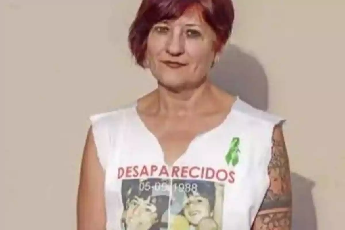Mujer de cabello corto y rojizo con camiseta blanca que tiene la palabra desaparecidos y fotos impresas en el frente Mujer de cabello corto y rojizo con camiseta blanca que tiene la palabra desaparecidos y fotos impresas en el frente