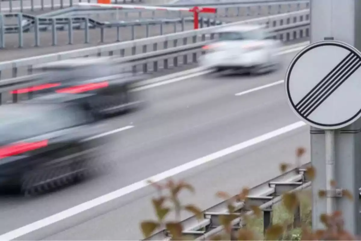 Autos circulando a alta velocidad en una autopista junto a una señal de fin de límite de velocidad