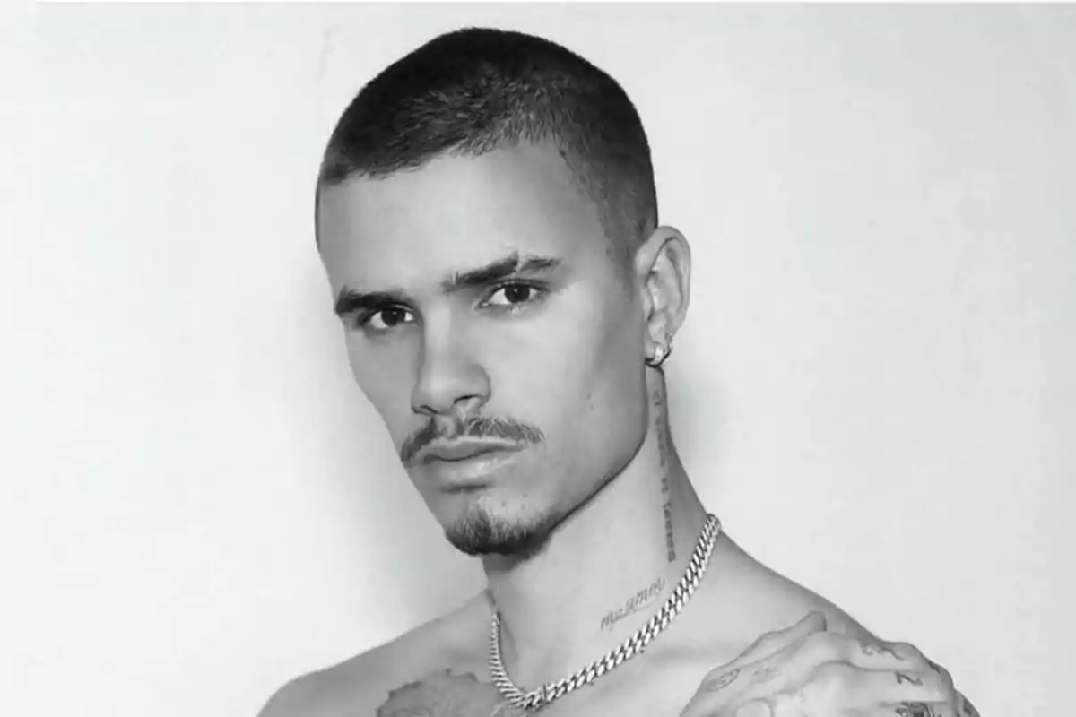 Joven con cabello corto y barba delgada mirando a la cámara en una foto en blanco y negro