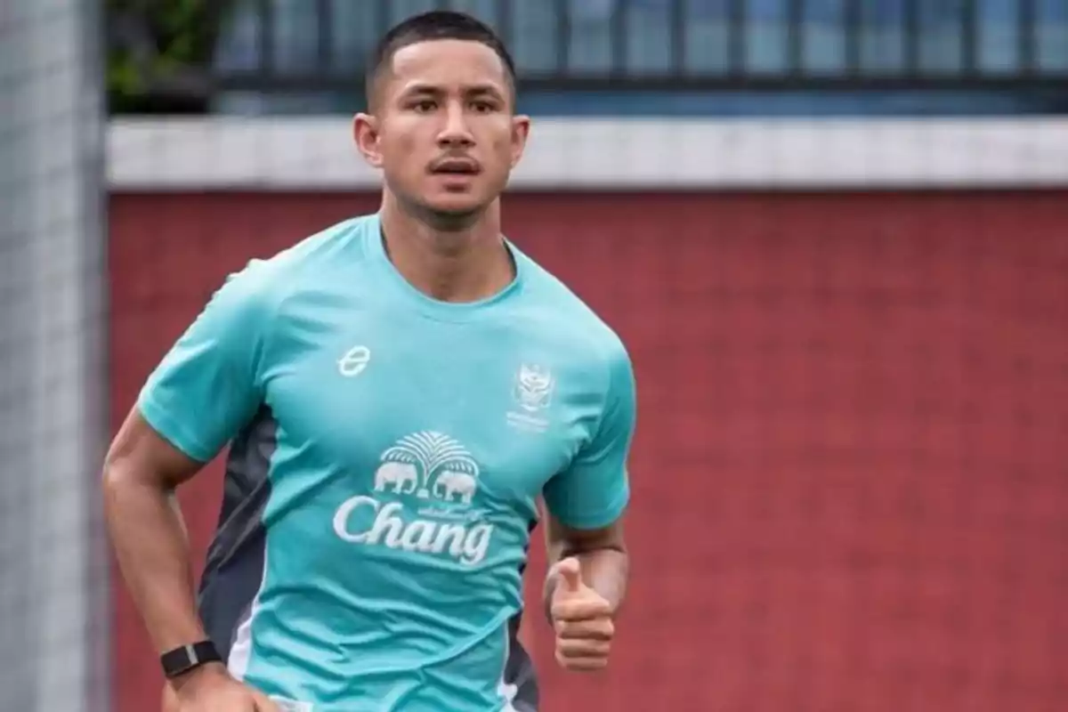 Hombre joven corriendo con camiseta deportiva celeste en un campo de fútbol Hombre joven corriendo con camiseta deportiva celeste en un campo de fútbol