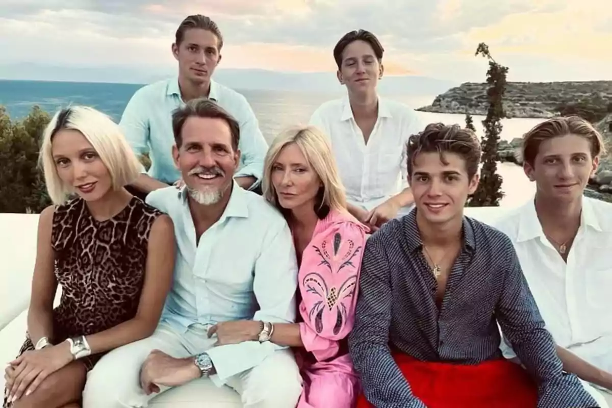 Siete personas posan sonrientes al aire libre con el mar y un paisaje rocoso de fondo durante el atardecer Siete personas posan sonrientes al aire libre con el mar y un paisaje rocoso de fondo durante el atardecer