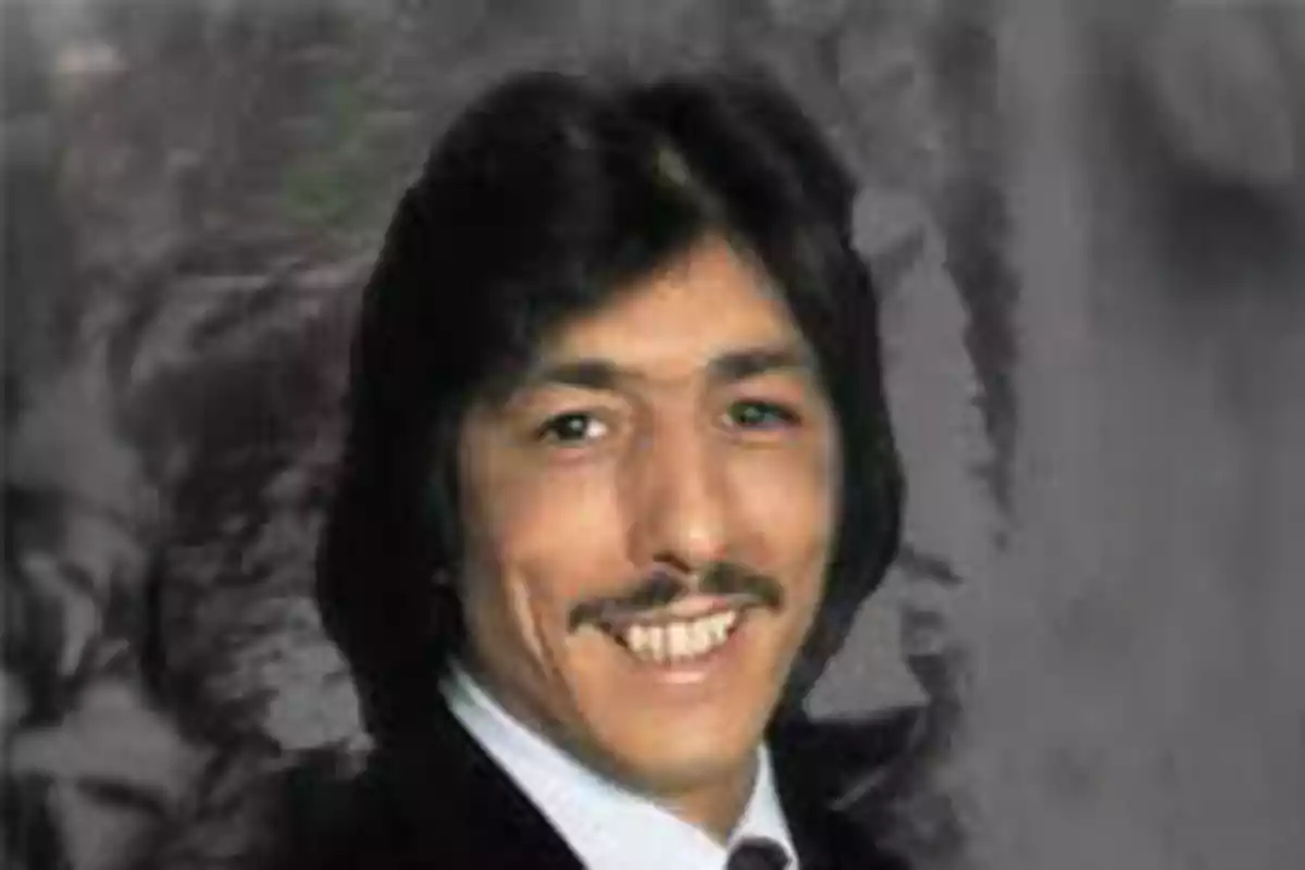 Hombre de cabello oscuro y bigote sonriendo con fondo gris difuminado