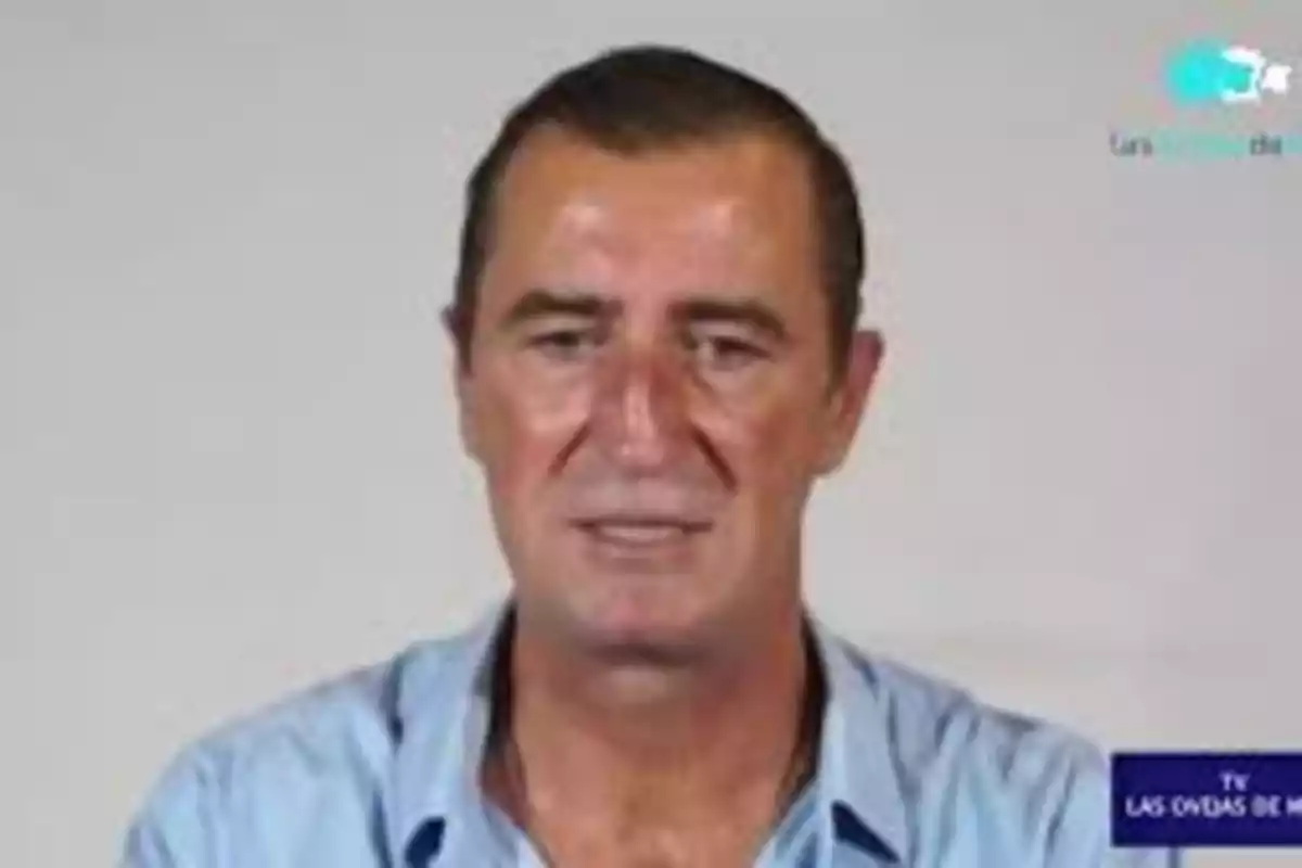 Hombre de cabello corto y oscuro con camisa azul claro posando frente a un fondo liso Hombre de cabello corto y oscuro con camisa azul claro posando frente a un fondo liso