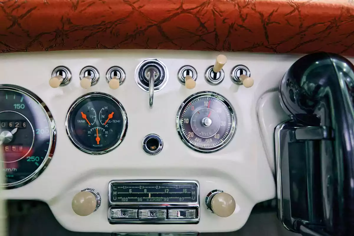 Tablero de automóvil clásico con velocímetro, indicadores analógicos, interruptores y radio antigua Tablero de automóvil clásico con velocímetro, indicadores analógicos, interruptores y radio antigua