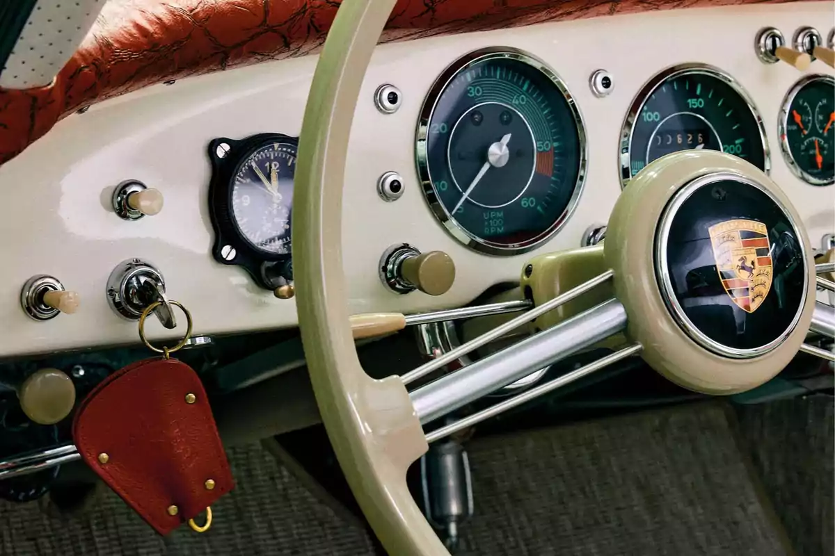 Tablero clásico de un automóvil Porsche con volante beige, velocímetro, tacómetro y llavero de cuero rojo Tablero clásico de un automóvil Porsche con volante beige, velocímetro, tacómetro y llavero de cuero rojo