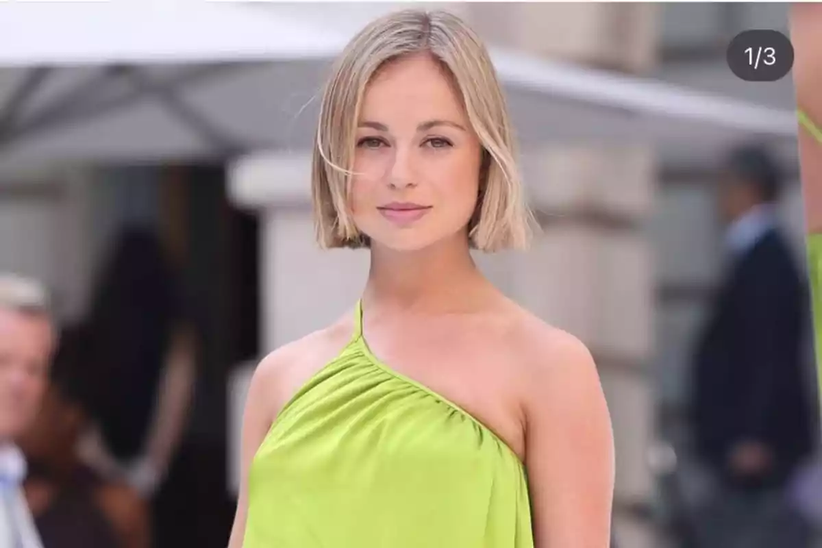 Mujer rubia con cabello corto usando un vestido verde de un solo tirante en un evento al aire libre Mujer rubia con cabello corto usando un vestido verde de un solo tirante en un evento al aire libre