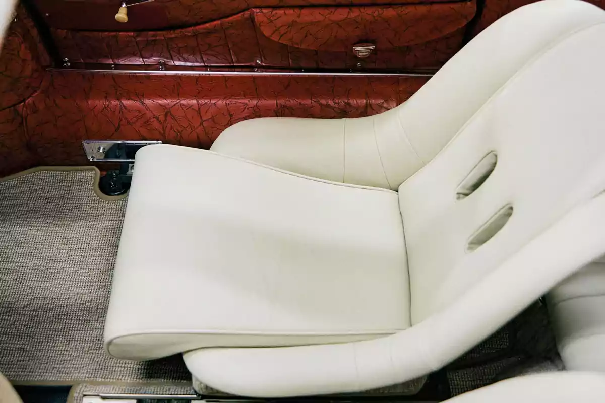 Asiento de automóvil clásico tapizado en color crema con interior de puertas en cuero marrón y alfombra beige Asiento de automóvil clásico tapizado en color crema con interior de puertas en cuero marrón y alfombra beige