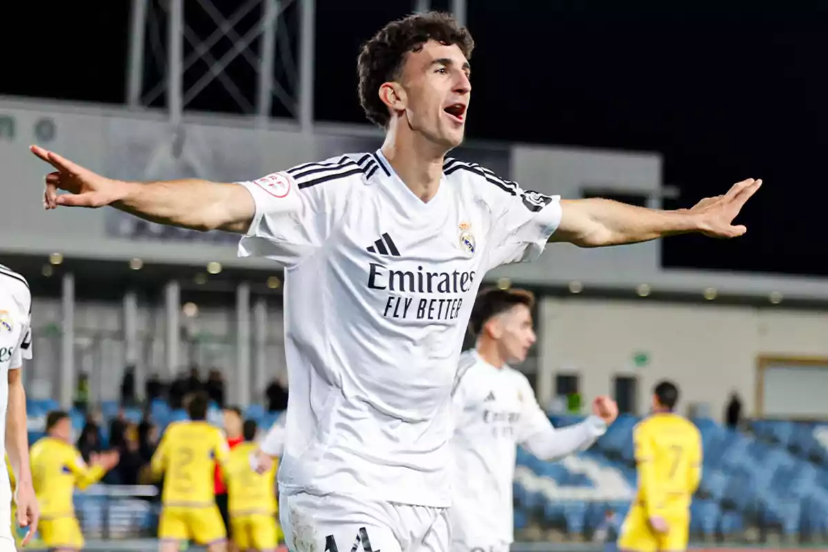 Futbolista del Real Madrid celebrando un gol con los brazos extendidos en un estadio durante un partido nocturno Futbolista del Real Madrid celebrando un gol con los brazos extendidos en un estadio durante un partido nocturno