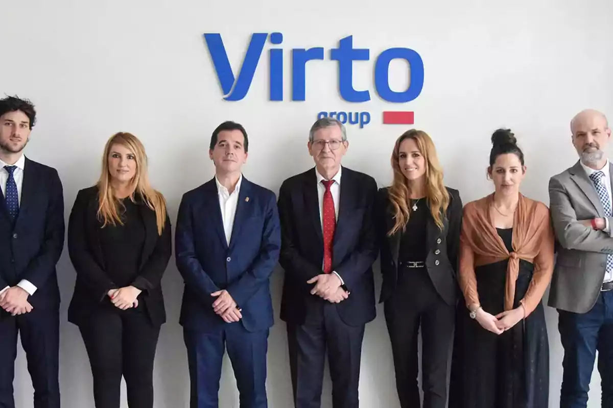 Siete personas vestidas de manera formal posan frente a una pared blanca con el logo de Virto Group. Siete personas vestidas de manera formal posan frente a una pared blanca con el logo de Virto Group.