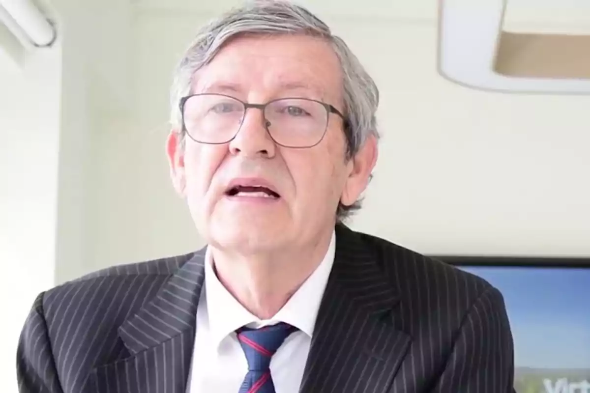 Hombre mayor con gafas y cabello canoso usando traje de rayas y corbata en una oficina