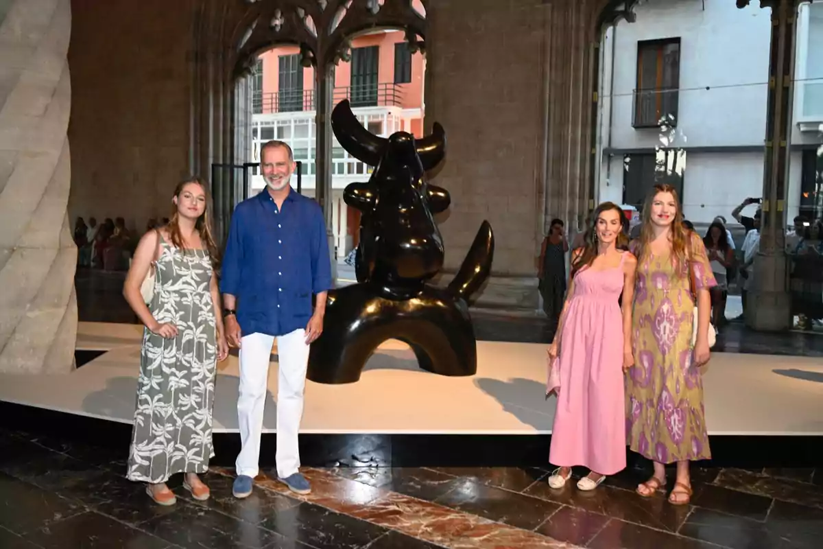 Cuatro personas posan frente a una escultura negra de forma abstracta en el interior de un edificio histórico con grandes ventanales y columnas Cuatro personas posan frente a una escultura negra de forma abstracta en el interior de un edificio histórico con grandes ventanales y columnas