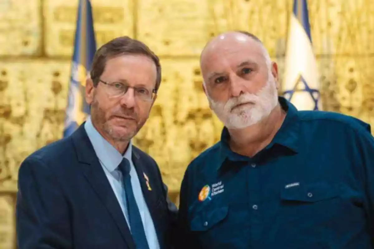 Dos hombres posan juntos frente a un fondo dorado con banderas de Israel al fondo