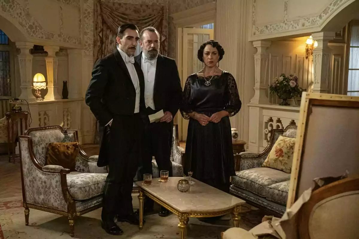 Lorenzo, Alonso y Leocadia elegantemente vestidas están de pie en una lujosa sala de estar antigua, observando algo fuera de cámara con expresiones serias. Captura de 'La Promesa' Lorenzo, Alonso y Leocadia elegantemente vestidas están de pie en una lujosa sala de estar antigua, observando algo fuera de cámara con expresiones serias. Captura de 'La Promesa'
