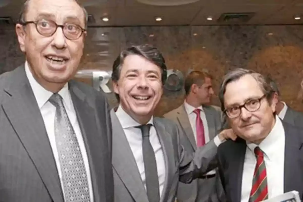Tres hombres con traje y corbata posan sonrientes en un evento empresarial en un ambiente interior elegante Tres hombres con traje y corbata posan sonrientes en un evento empresarial en un ambiente interior elegante