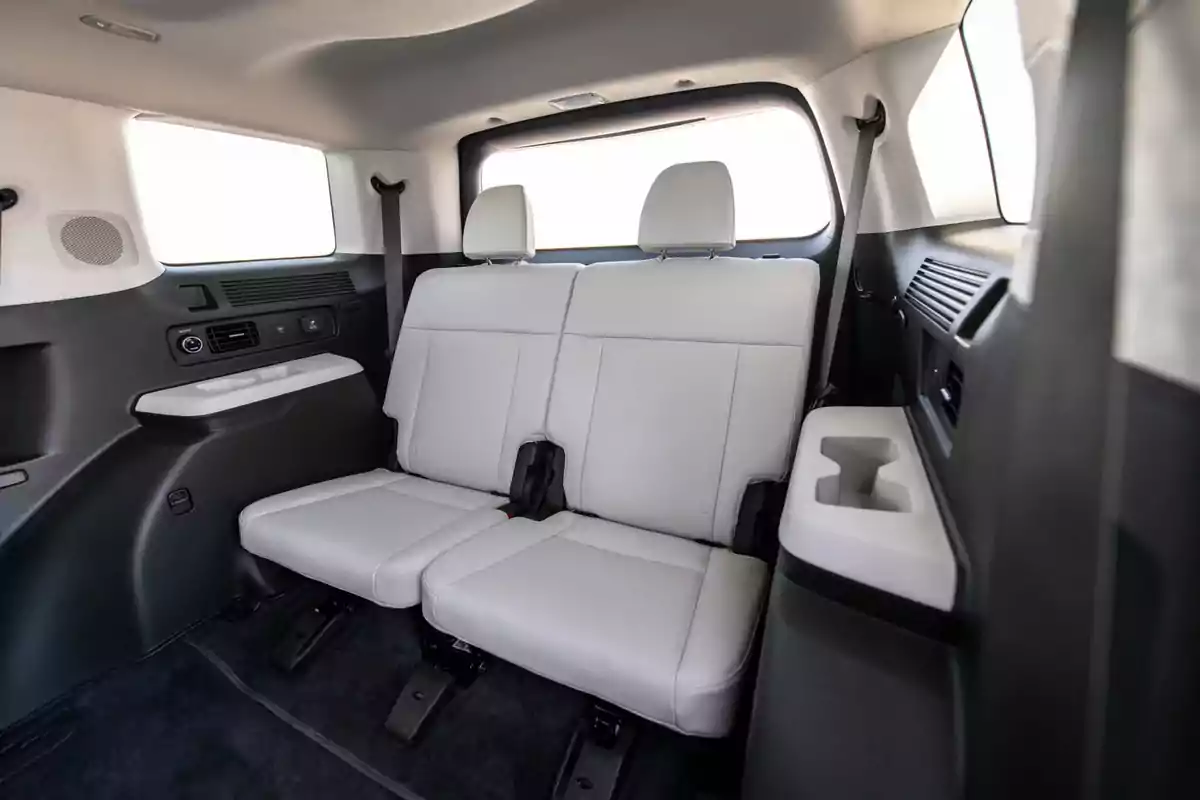 Asientos traseros de una camioneta con tapicería clara y portavasos integrados Asientos traseros de una camioneta con tapicería clara y portavasos integrados