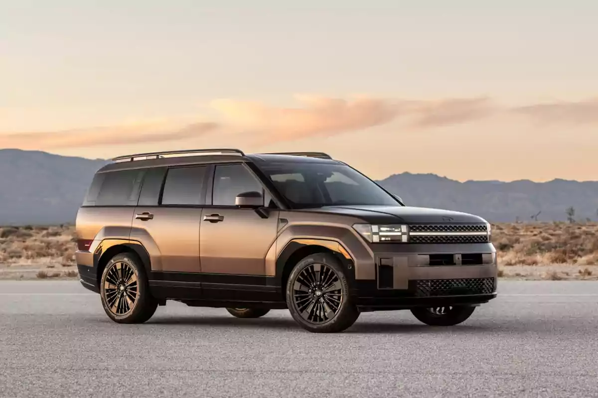 SUV moderna de color cobre estacionada en una carretera con paisaje desértico y montañas al fondo al atardecer SUV moderna de color cobre estacionada en una carretera con paisaje desértico y montañas al fondo al atardecer