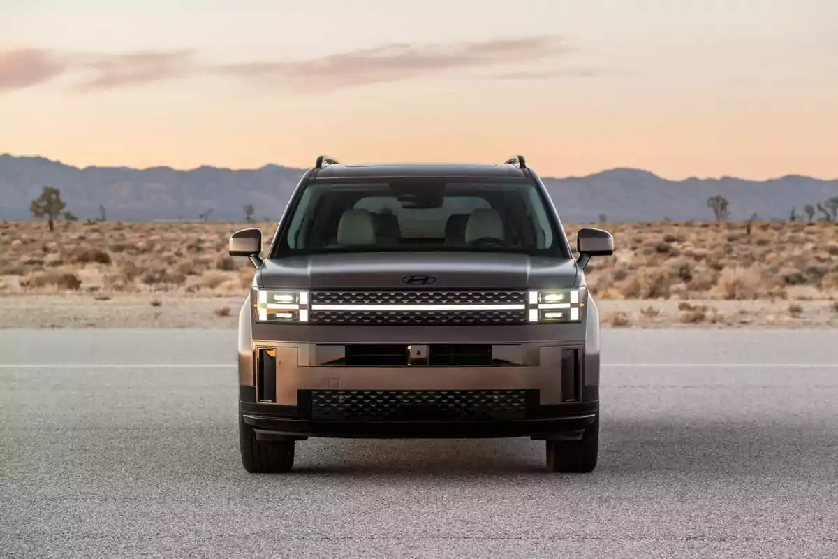 SUV gris vista de frente estacionada en una carretera en medio del desierto al atardecer SUV gris vista de frente estacionada en una carretera en medio del desierto al atardecer