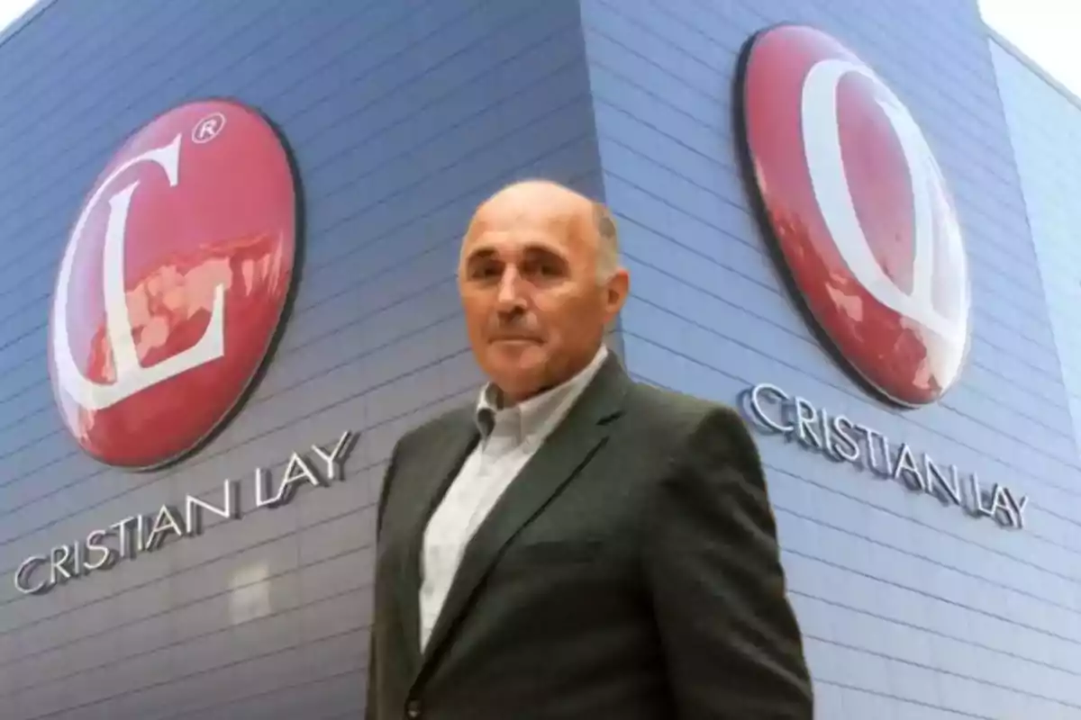 Hombre de traje posando frente a un edificio con logotipos grandes de Cristian Lay en la fachada