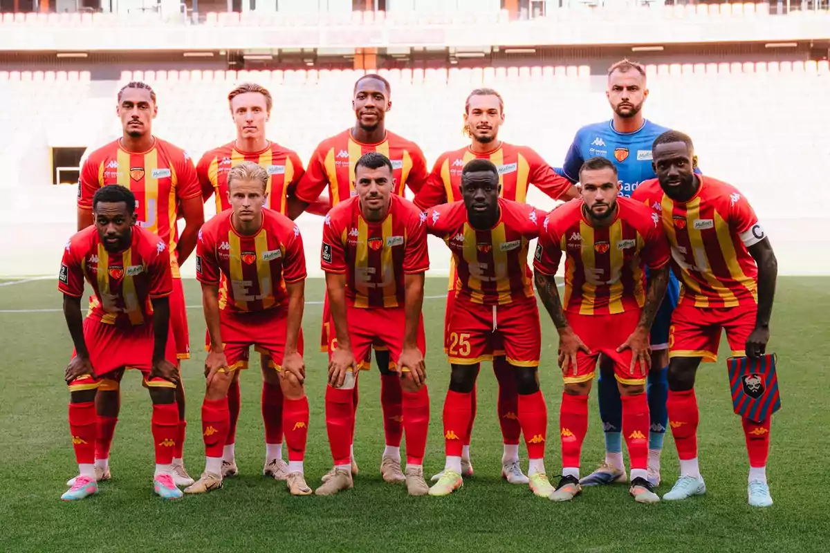 Once jugadores de fútbol posan juntos en el campo con uniforme rojo y amarillo antes de un partido Once jugadores de fútbol posan juntos en el campo con uniforme rojo y amarillo antes de un partido