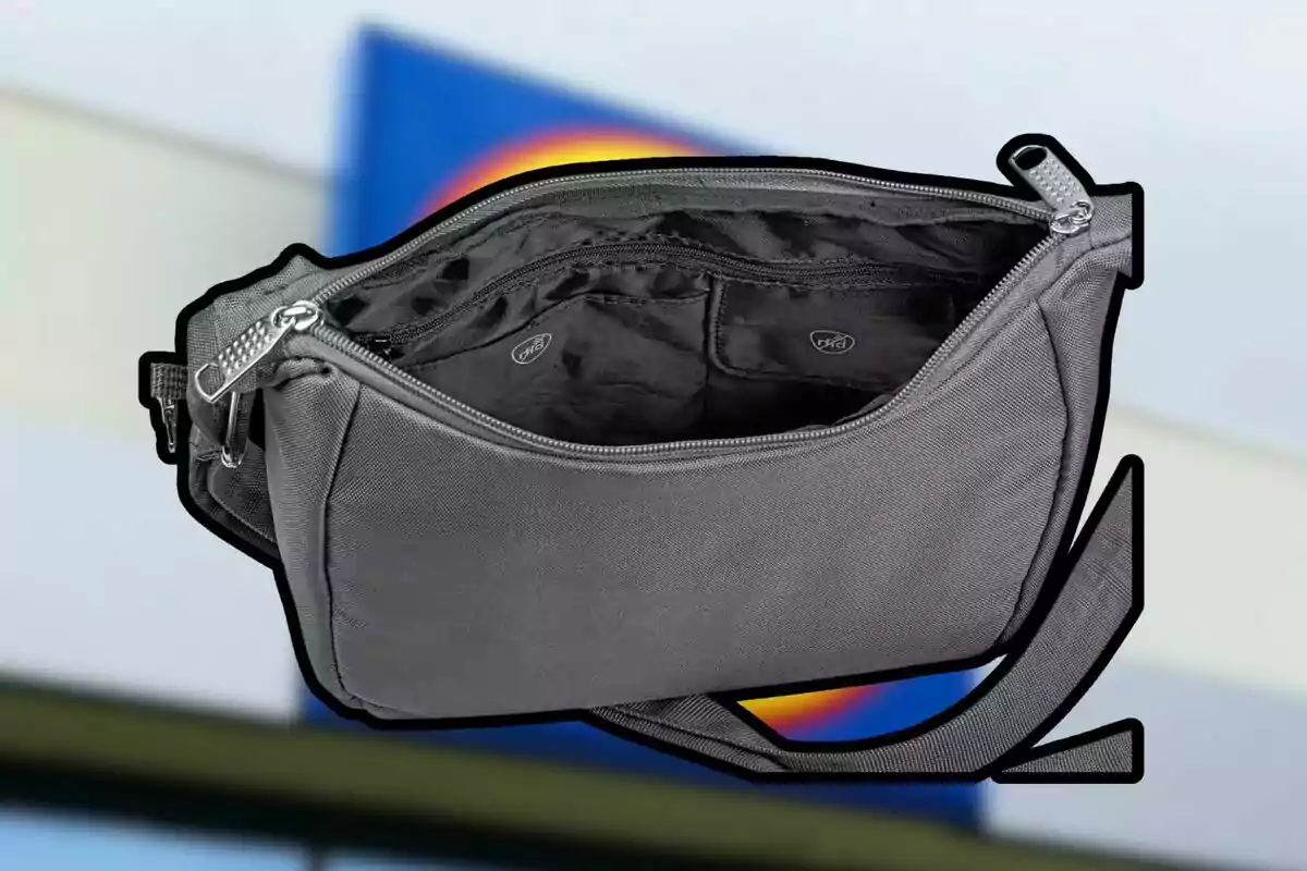 Bolso gris de tela con cierre abierto mostrando el interior y varios compartimentos, sobre un fondo desenfocado con colores azul y amarillo. Bolso gris de tela con cierre abierto mostrando el interior y varios compartimentos, sobre un fondo desenfocado con colores azul y amarillo.