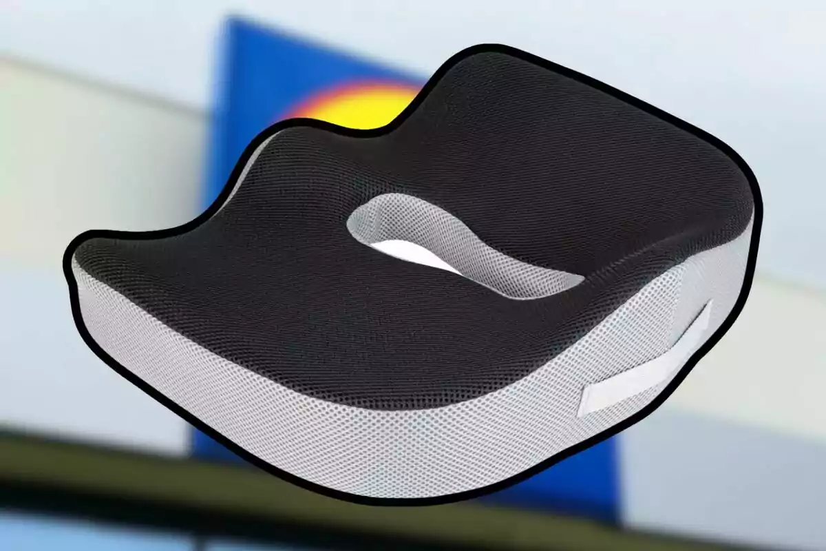 Cojín ergonómico negro y blanco con orificio central y asa lateral sobre un fondo desenfocado Cojín ergonómico negro y blanco con orificio central y asa lateral sobre un fondo desenfocado