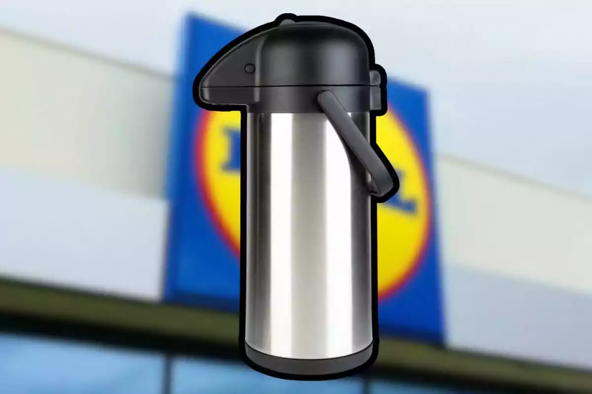 Termo dispensador de acero inoxidable con tapa y asa negra frente a un letrero borroso de una tienda Termo dispensador de acero inoxidable con tapa y asa negra frente a un letrero borroso de una tienda