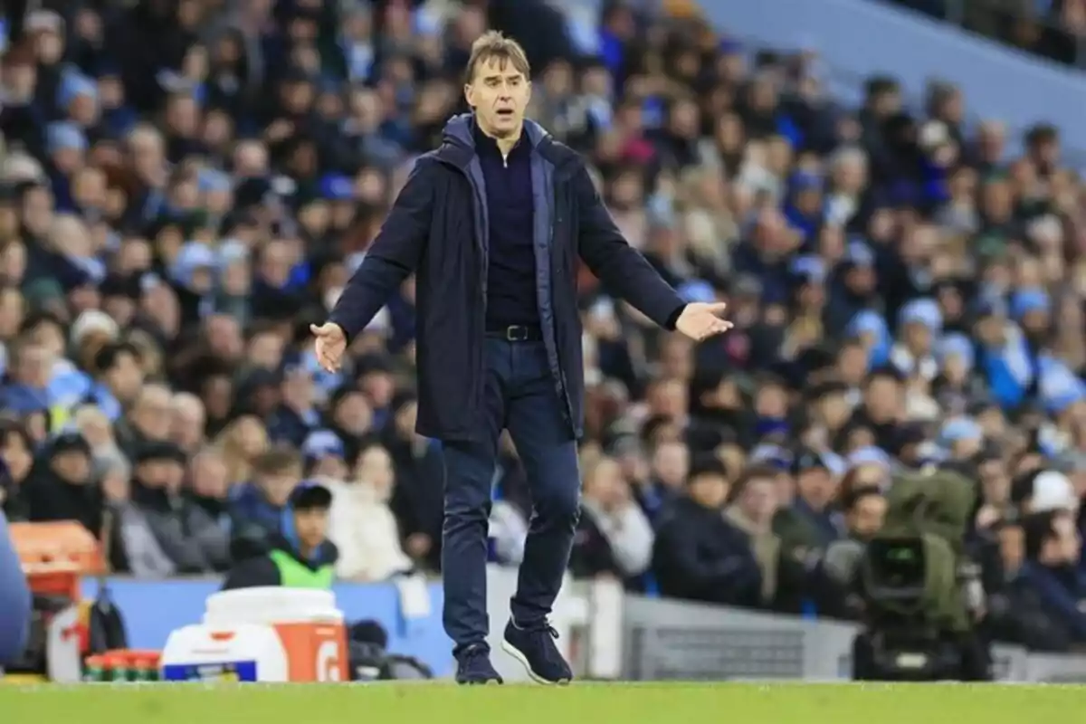 Entrenador de fútbol en la línea de banda con los brazos abiertos mostrando una expresión de sorpresa durante un partido con el público de fondo. Entrenador de fútbol en la línea de banda con los brazos abiertos mostrando una expresión de sorpresa durante un partido con el público de fondo.