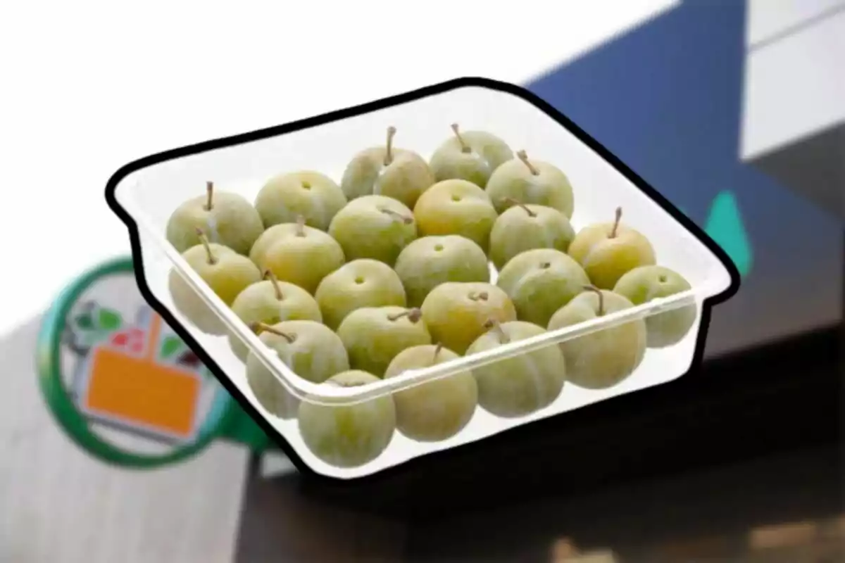 Bandeja de ciruelas verdes sobre un fondo borroso de supermercado Bandeja de ciruelas verdes sobre un fondo borroso de supermercado