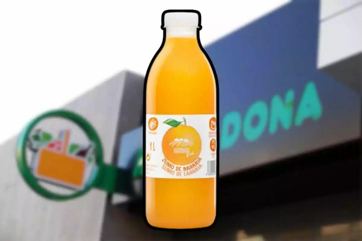 Botella de zumo de naranja Hacendado frente a una tienda Mercadona desenfocada Botella de zumo de naranja Hacendado frente a una tienda Mercadona desenfocada