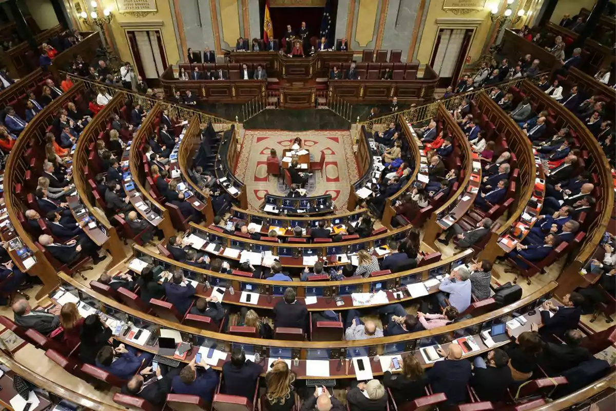 Vista panorámica del interior de un parlamento con numerosos diputados sentados en semicírculo durante una sesión plenaria