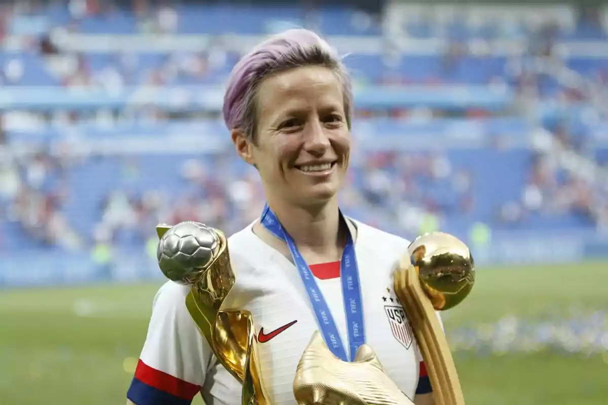 Futbolista estadounidense sonriente sostiene trofeos y medalla en un estadio tras ganar un campeonato Futbolista estadounidense sonriente sostiene trofeos y medalla en un estadio tras ganar un campeonato