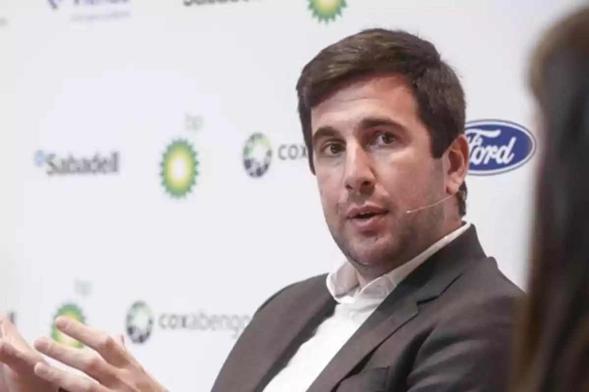 Hombre con micrófono de diadema hablando en un evento con logotipos de empresas en el fondo Hombre con micrófono de diadema hablando en un evento con logotipos de empresas en el fondo