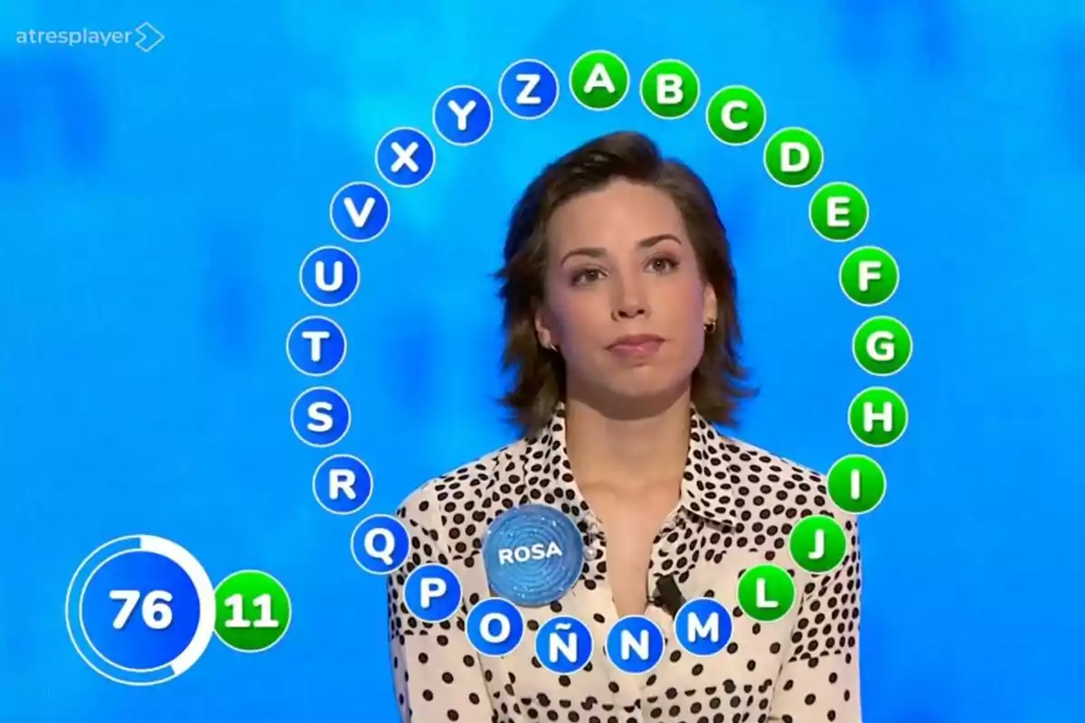 Una concursando en un programa de televisión, que es Rosa Rodríguez en 'Pasapalabra', con letras del abecedario rodeándola y un marcador de tiempo y aciertos en pantalla. Una concursando en un programa de televisión, que es Rosa Rodríguez en 'Pasapalabra', con letras del abecedario rodeándola y un marcador de tiempo y aciertos en pantalla.