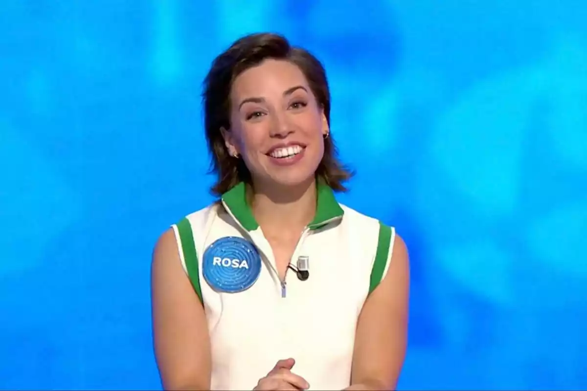 Rosa Rodríguez sonriente con cabello corto y oscuro, vestida con camiseta sin mangas blanca con detalles verdes y un gafete azul que dice Rosa, sobre un fondo azul. Rosa Rodríguez sonriente con cabello corto y oscuro, vestida con camiseta sin mangas blanca con detalles verdes y un gafete azul que dice Rosa, sobre un fondo azul.