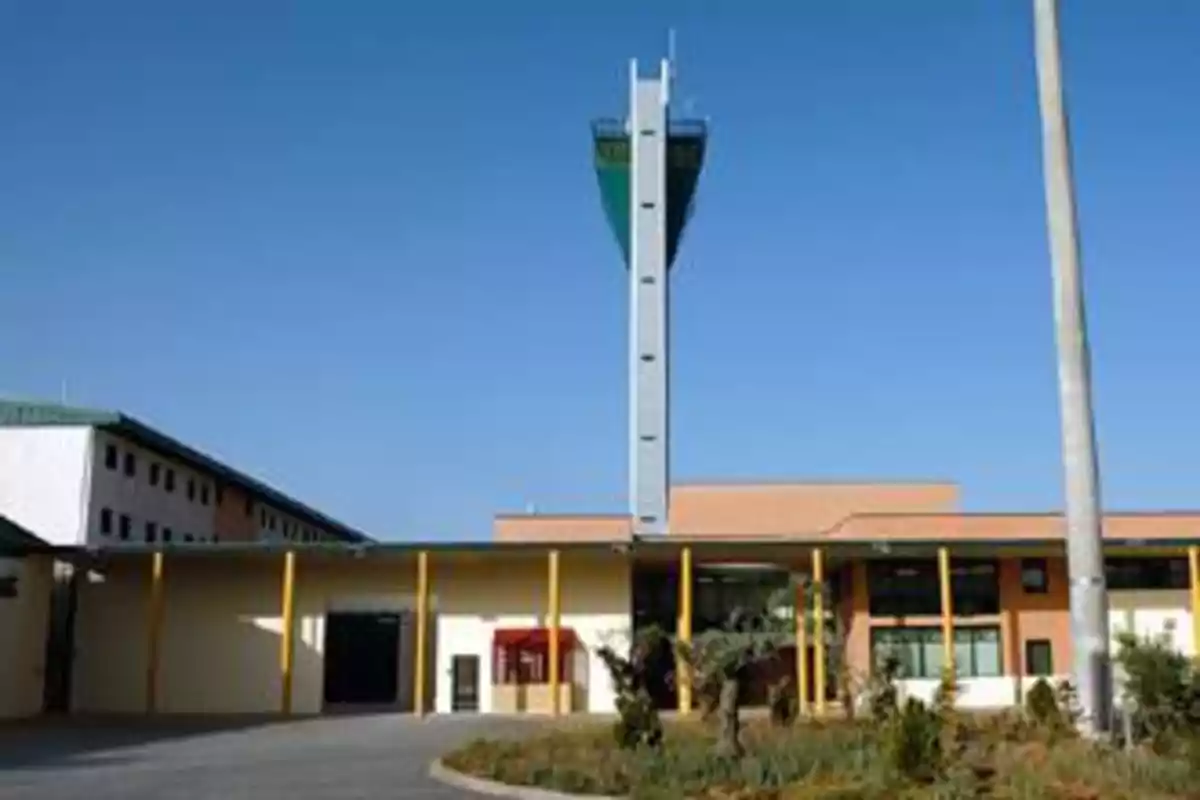 Edificio con una torre alta en el centro y columnas amarillas en la entrada bajo un cielo despejado Edificio con una torre alta en el centro y columnas amarillas en la entrada bajo un cielo despejado