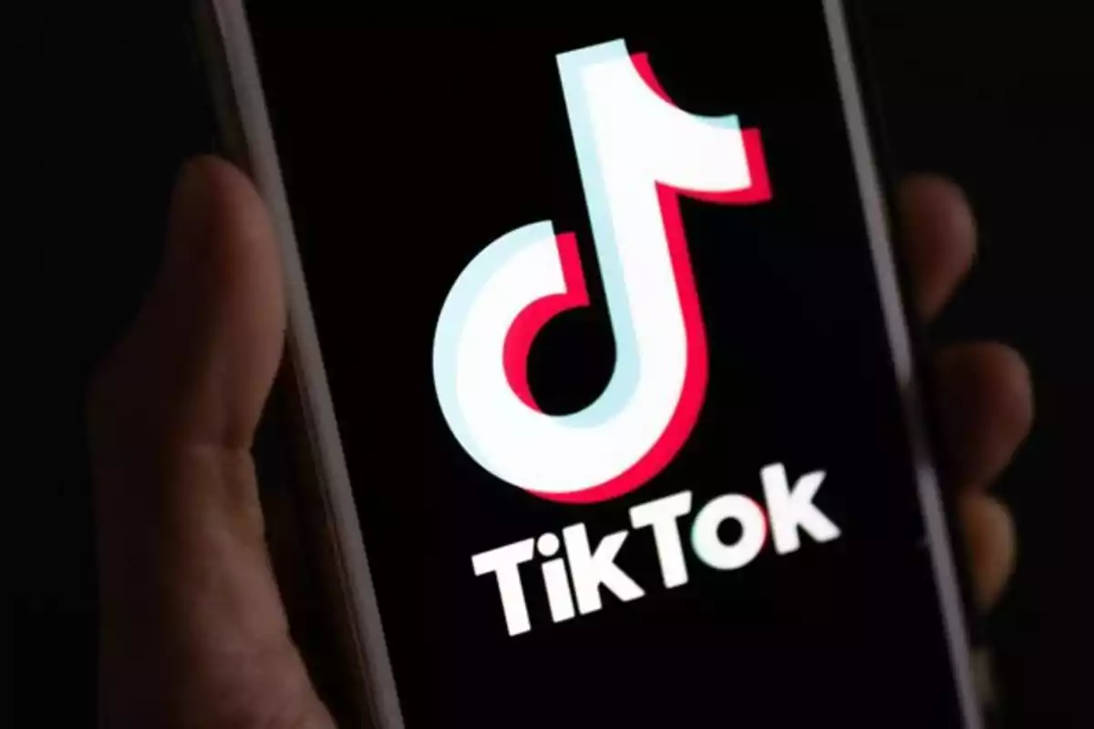 Persona sosteniendo un teléfono móvil que muestra el logo de TikTok en la pantalla Persona sosteniendo un teléfono móvil que muestra el logo de TikTok en la pantalla