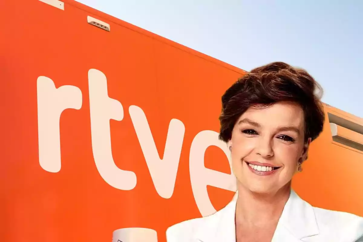 Mujer sonriente con cabello corto y saco blanco frente a un fondo naranja con el logo de rtve