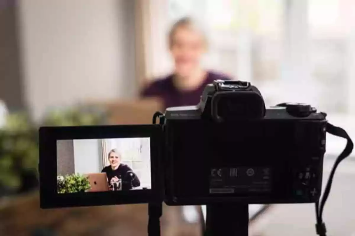 Persona grabando un video frente a una cámara digital con la pantalla mostrando su imagen