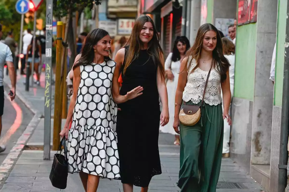 Tres mujeres jóvenes caminan sonrientes por una calle urbana, vestidas con ropa veraniega y casual, disfrutando de un paseo juntas. Tres mujeres jóvenes caminan sonrientes por una calle urbana, vestidas con ropa veraniega y casual, disfrutando de un paseo juntas.