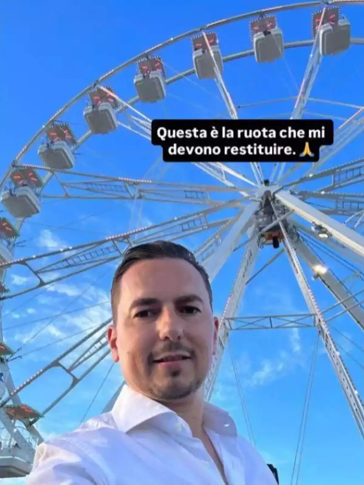 Hombre tomándose una selfie frente a una rueda de la fortuna con el cielo azul de fondo y un texto en italiano sobre la imagen. Hombre tomándose una selfie frente a una rueda de la fortuna con el cielo azul de fondo y un texto en italiano sobre la imagen.