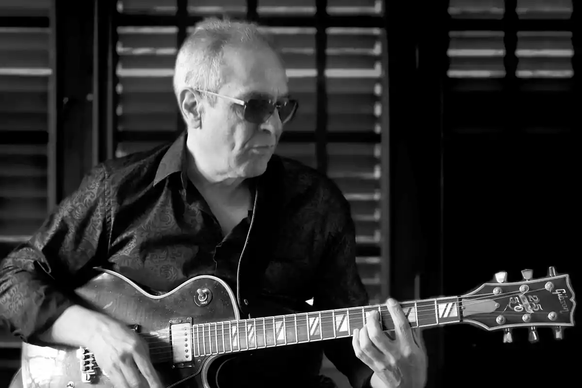 Hombre mayor con gafas de sol tocando una guitarra eléctrica en blanco y negro Hombre mayor con gafas de sol tocando una guitarra eléctrica en blanco y negro