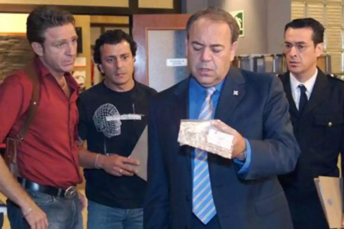 Four men in an office watch a package that one of them is holding carefully. Four men in an office watch a package that one of them is holding carefully.